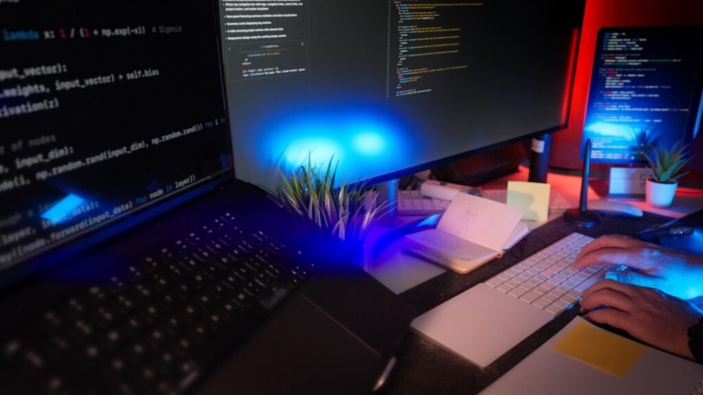 Persona programando una página web con apoyo de inteligencia artificial en un escritorio con varias pantallas