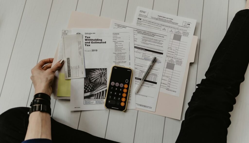 Persona organizando un presupuesto con documentos, calculadora y bolígrafo